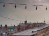 A photograph of a string of unlit lamps strung above an urban landscape