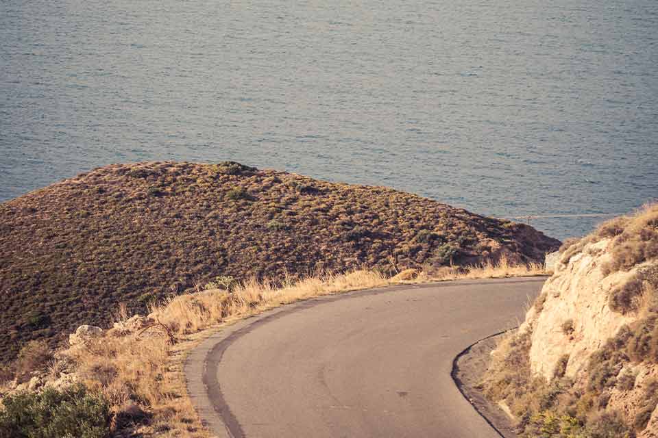 A faded color photograph of a mountain road winding out of view