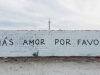 A photograph of a long wall with graffiti on. Text reads: Mas Amor Por Favor 