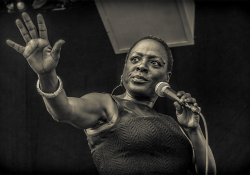 A photograph of Sharon Jones singing