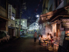 A group of people sit at a table in front of a street vendor in Nagoya, Japan