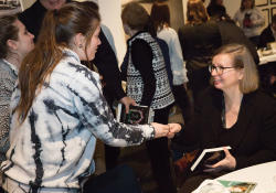 Jenny Erpenbeck is seated, greeting two women who are attending the opening night reception