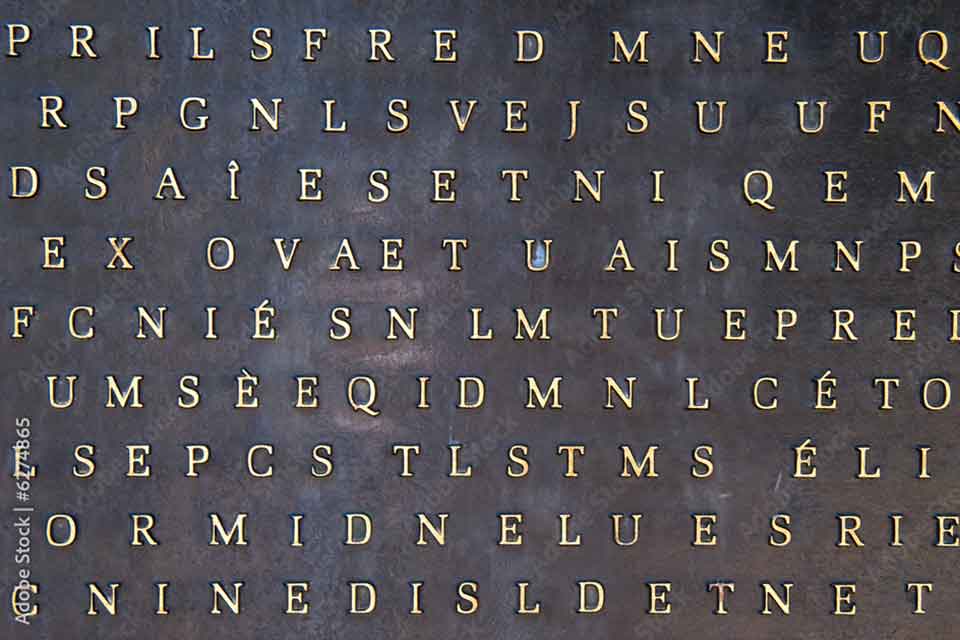 A metal tile with letters printed on it. They do not spell words.