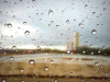 A photograph of a rural landscape, blurred by rain drops