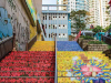 A long flight of stairs in a crowded city. The stairs are painted with red and yellow flowers. 