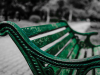 Close-up of a wooden bench, painted forest green, though the paint has begun to wear out with age and use