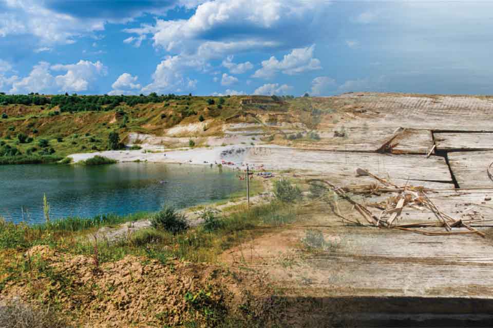 A digital collage. A photograph of a lake bordered by a rocky ridge that blends into a photograph of a worn-wooden raft.