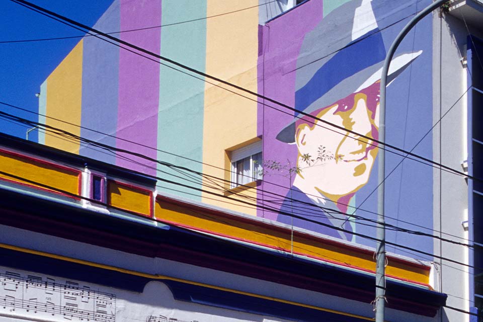 A photograph of a mural featuring a man's face, dressed in a dress suit and hat