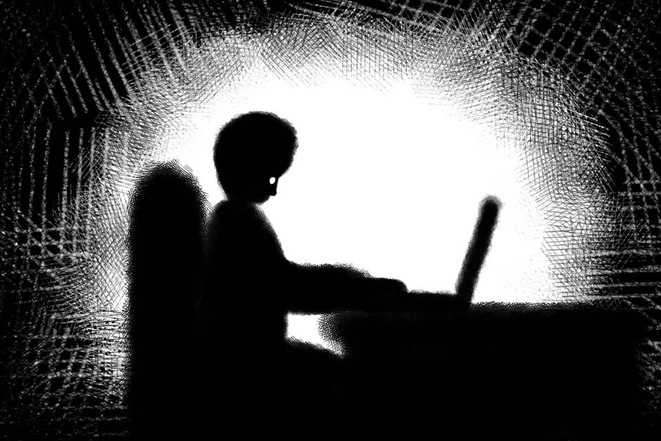 An illustration of a figure in shadow typing on a computer