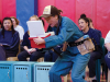 Spectators watch as an actor in costume peers inside of a mini-cooler