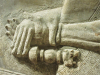 A bas-relief sculpture of hands clasping across the wrist