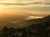 A photograph looking from up on high down at a river valley in the golden morning sun