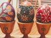 A photograph of three ornately lacquered eggs resting in wooden stands