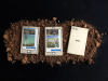 Three disheveled electronic tablets laying on a bed of soil. The third is turned face down