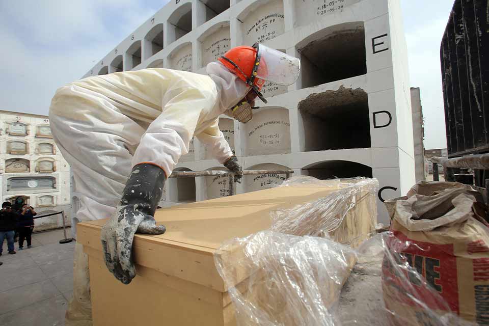 A photograph of men in hazmat suits moving a body